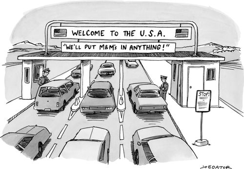 Sign at a border crossing saying "Welcome to the U.S.A. - We'll put M&M's in anything!"