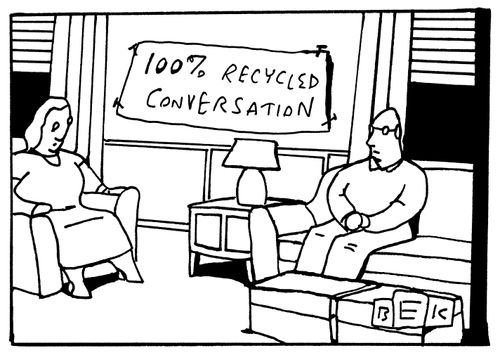 Man and a woman sit in a living room; a sign on the wall behind them reads "100% Recycled Conversation".