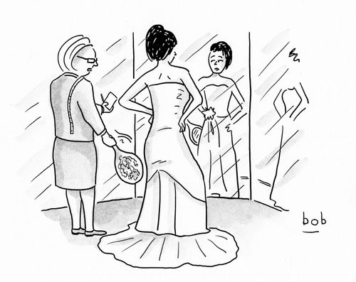 Saleswoman holds mirror up to the backside of the bride's dress