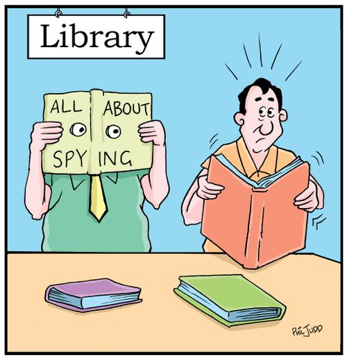 Man reading a book in the library. Notices a man next to him reading all book about spying.
