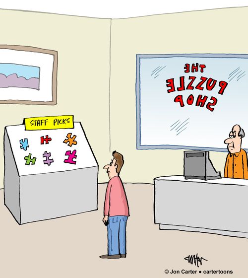 Man in puzzle shop looks at staff picks which are individual puzzle pieces.