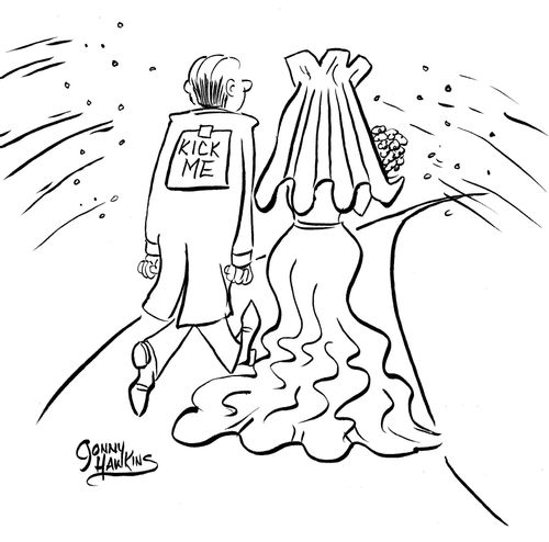 Groom and bride walk out of church as rice is thrown. Groom has sign on back 'Kick Me'.