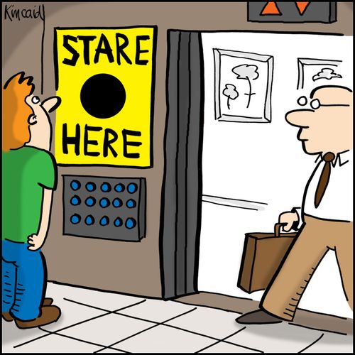 Man in elevator looking at sign that says 'Stare Here.'