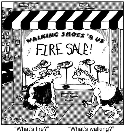 Two Neanderthals standing in front of a store, 'Walking Shoes ‘R Us,' which is having a 'Fire Sale.' One asks, 'What's fire?' The other asks, 'What's walking?'