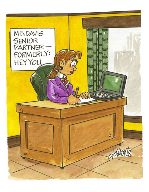 woman works at a desk with a sign on the wall behind her: Ms. Davis Senior Partner - Formerly Hey You.