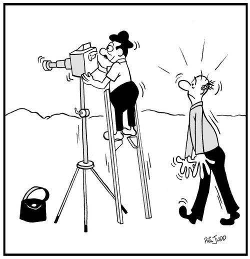 Short man standing on stilts to take a picture with a camera on a tripod.