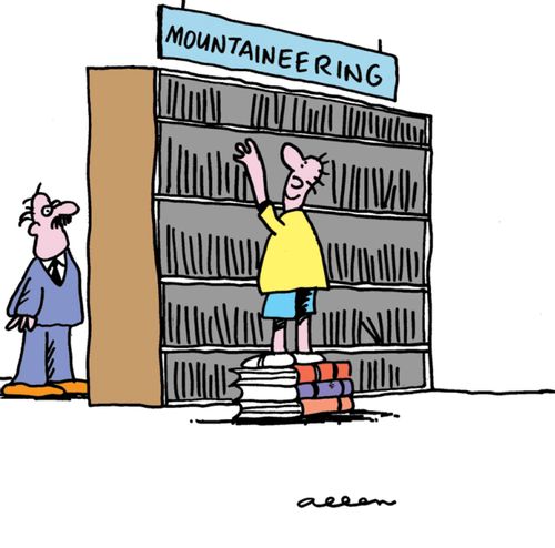 Man in library standing on pile of books looking in mountaineering section.