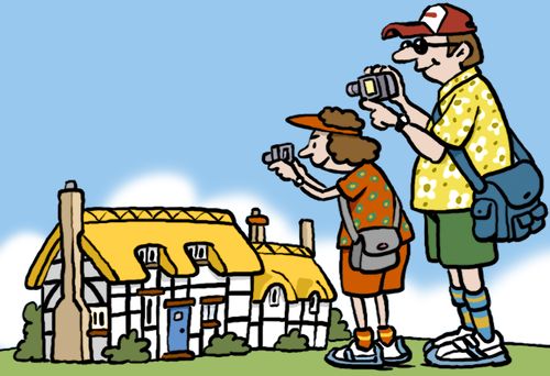 Tourists filming a thatched cottage.