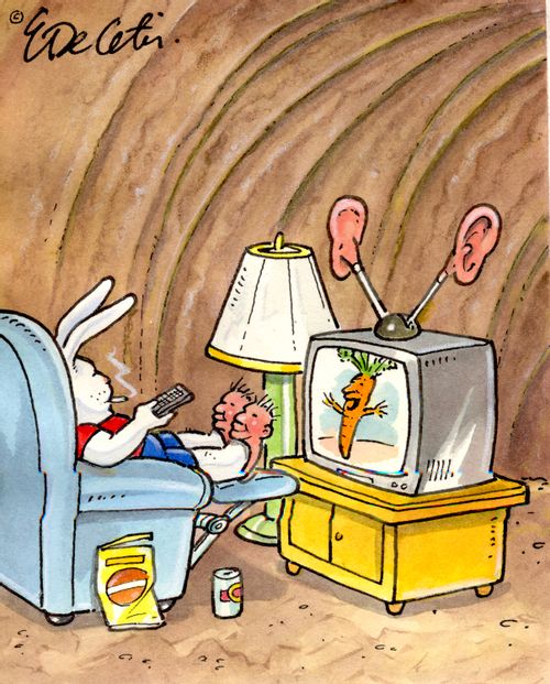 A bunny watches TV while wearing slippers shaped like a human head.
