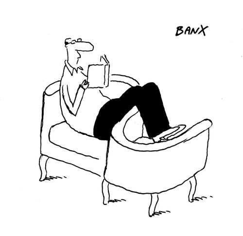 A man sitting on a S shaped chair reading a book